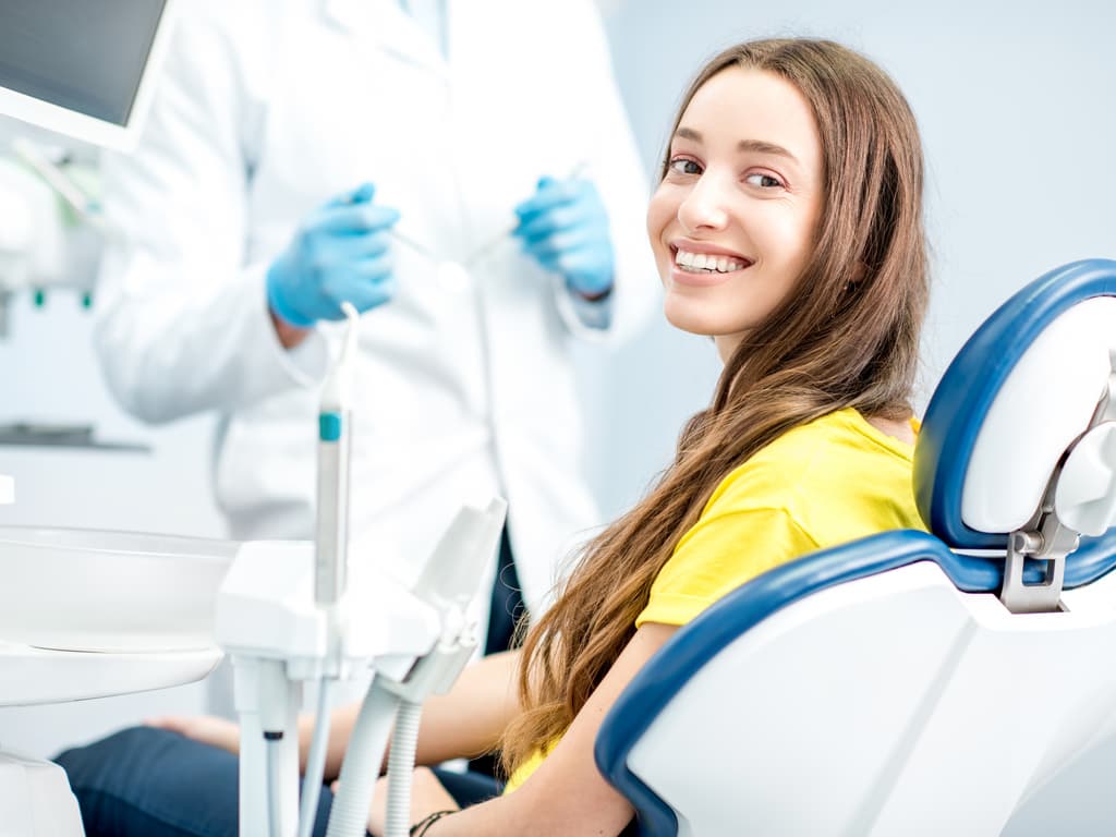 femme souriante sur fauteuil dentiste